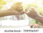Small photo of close up hands of lovely couple hooking each other's little finger together with copy space for text and soft light effect: pinky swear, pinkie promise concept