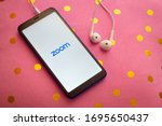 Small photo of Puebla, Mexico - April 6, 2020: Zoom mobile application on a smartphone with headphones on a pink cushion. Zoom users can choose to record sessions, collaborate on projects, and share or annotate o