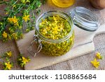 Small photo of St. John's wort flowers macerating in olive oil in a glass jar