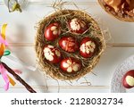 Easter eggs dyed with onion peels in a wicker basket, with pomlazka - Czech symbol of spring, on white background
