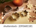 Cutting out flower and star shapes from pastry dough to prepare Linzer Christmas cookies, close up