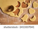 Cutting out star and bell shapes from pastry dough to prepare Linzer Christmas cookies, top view