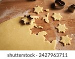 Cutting out star shapes from rolled out dough to prepare Linzer Christmas cookies