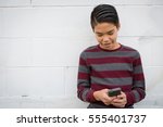 Happy, smiling teenage Asian boy having fun using his smartphone, isolated against. Teen social concepts:  connection with friends, power of social media, new communication styles
