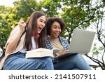 Small photo of Happy smiling young diversity woman with happy college friends in background at the summer park. Multiethnic and diversity student doing homework and submit assignments to teachers. Education Concept.