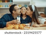 Small photo of Family Love. Caring parents kissing their tittle daughter while drinking bottle of milk, Bonding together at Home