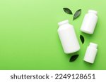 Small photo of supplement pills with medicine bottle health care and medical top view. Vitamin tablets. Top view mockup bottle for pills and vitamins with green leaves, natural organic bio supplement, copy space.
