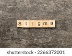 Small photo of stigma word written on wood block. stigma text on table, concept.