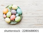 Happy Easter composition. Easter eggs in basket on colored table with gypsophila. Natural dyed colorful eggs background top view with copy space.