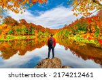 Lake scenery in autumn. Autumn colors in nature. Autumn landscape in forest. European traveler watching lake view among colorful trees. European man making new discoveries in colorful autumn in nature