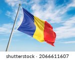 3d rendering Romania flag waving in the wind on flagpole. Perspective wiev Romania flag waving a blue cloudy sky