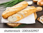 Half an onion baguette on a towel, French bread, wooden background