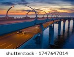 Two-level road bridge over the water. Traffic on the motorway in the evening. Cars drive across the bridge against the evening sky. Night road on two levels. Speedway over the water. 