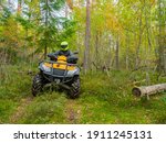 Small photo of ATV rider during motocross. ATV rides through the forest. Man on a yellow quad cycle. ATV rider in taiga. He participates in an off-road race. Motocross in forest. Extreme sport on a bike