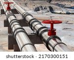 Small photo of Gas pipeline. Two gas pipes with red valves. Pipeline for transfer of hydrocarbons. Steel pipeline on rocks. Gas start and import concept. Sale of propane and methane.