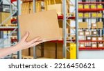 Small photo of Box in bonded warehouse. Womans hand with box. Box in front of blurred shelving. Concept customs checks at border. Processing of goods at customs. Sending parcels through customs.
