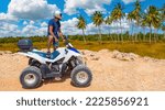 Small photo of ATV driver in tropical area. Man with ATV examines palm trees. Concept of extreme tourism. Quad bike driver in helmet looks into distance. ATV racing in tropical area. Man with quad bike