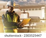 Small photo of Man technologist with laptop. Oil industry. Guy near plan building. Oil refinery technologist. Pipes with tanks behind engineer. Technician controls oil refining process. Man near industrial hangar