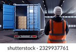 Small photo of Truck with container. Man logistician with his back to camera. Truck inside industrial hangar. Pallets with boxes delivered to warehouse. Parcel in back of truck. Logistician in industrial building