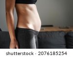 Young woman side view of body. Swollen belly. Pregnancy. Diastasis recti after child birth. Fitness exercises and diet for weight loss. 