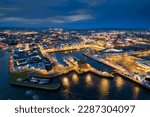 Illuminated port town at night. Aerial view on River Corrib and Galway city, Ireland. Dark sky. Popular educational center and tourist hub with vivid night life.
