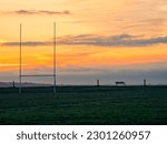 Small photo of Silhouette of a tall goal post for Irish National sports comogie, hurling, rugby and gaelic football against blue and orange sun rise sky.