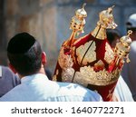 Small photo of Jewish man in black kippah carrying a Torah scroll in a beautifully ornate red case with golden bells and crowns (rimmonim) and other decorations - Simchat Torah; Western/Wailing Wall, Jerusalem