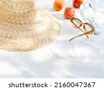 Vintage inspired background with straw hat, female sunglasses, bottle of water  and fruits on white towel. Minimalist summer vacation creative still life ​for fashion blog, web, social media, stories.