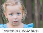 Sweet little girl, three years old. The girl smiles, looks into the camera. blonde girl with Blue eyes.Concept: summer, holidays, happy childhood.Little girl looks at the camera