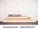 The word Policy, alphabet on wooden rubber stamps on top of books and table. Bricks background, blank copy space, vintage minimal style. Business privacy legal documents, advice information concepts.
