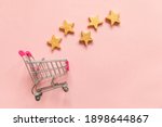Simply flat lay design small supermarket grocery push cart for shopping and 5 gold stars rating isolated on pink pastel background. Retail consumer buying online assessment and review concept
