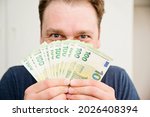 Small photo of The Smell of Euro. Scent of a money. Man covering face with hundreds of Euro banknotes. Gamblers look. Financial machinations, fraud, swindle, tax evasion.