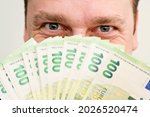 Small photo of The Smell of Euro. Scent of a money. Man covering face with hundreds of Euro banknotes. Gamblers look. Financial machinations, fraud, swindle, tax evasion.