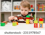 Small photo of Learning to count. 2 year old boy stacking Duplo blocks. children, infancy and education concept. formation and development of the child. Montessori and early development