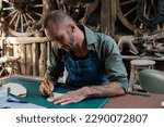 Small photo of Handcrafted leather worker sits farts cowhide with cutter according pattern drawn on leather, according pattern drawn before cutting, so that pattern cut on cowhide comes out beautiful sharp.