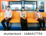 Three Asian people wearing mask sitting in subway distance for one seat from other people keep distance protect from COVID-19 viruses and people social distancing  for infection risk 

