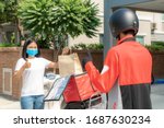 Small photo of Asian woman pick up delivery food bag from box and thumb up form contactless or contact free from delivery rider with bicycle in front house for social distancing for infection risk.