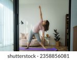 Small photo of Tranquil aura envelops as an Asian woman finds solace through yoga and meditation at home, a serene journey within four walls.
