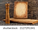 Small photo of Cutting board and salt shaker on a black shabby table. Shred peppers on a dark background. Copy space and free space for extras near cooking tools. sharpness on the salt shaker.