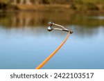 Small photo of bell alarm is on fishing rod spinning in nature bells of allure are attached to the end of the fishing spinning abandoned in water standing with stretched fishing line Bottom. fishing accessories.