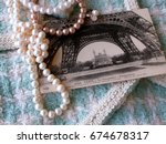  Vintage postcard of 1911 with the image of the Eiffel Tower, beads from pearls  on the background white and turquoise hand weaving matting tweed fabric texture. Chanel style concept. Closeup 
	
