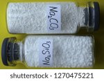 Small photo of Two glass jars with crystalline substances: silicate and sodium carbonate.