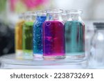 Small photo of A glass jar with an aqueous solution of a red organic dye on a background of other organic dyes.