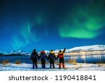Group Tourists visiting in Tromso. Amazing beautiful Aurora, also know as Northern Lights dancing over the night sky. Travel, tourism, holidays concept.