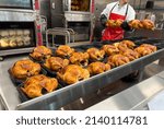 Small photo of Sacramento, CA, USA March 24th, 2022 Costco employee cooking famous affordable roasted chickens