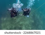 Small photo of Master diver and dive pupil preparing to ascend after dive training at shallow water. They wait at ascending dive stop for decompression be ready.