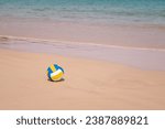 Ball at sandy beach close to seashore line. Blue yellow white stripes. Close up photo