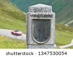 sign of the austrian county vorarlberg at the mountain road silvretta hochalpenstrasse, vintage car unsharp in the background