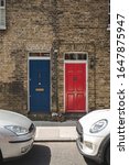 Small photo of Colorful bright red and blue doors on a facade of British terrace house.Terrace house is a form of medium-density housing that originated in Europe, whereby a row of attached dwellings share sidewalls