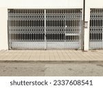Closed and abandoned city store with shutter security gates and padlock. Sidewalk and asphalt road in front. Background for copy space.